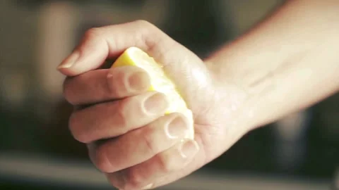 Closeup shot of person's hands squeezing lemon juice. Human squeezes half of Stock Footage 336588739