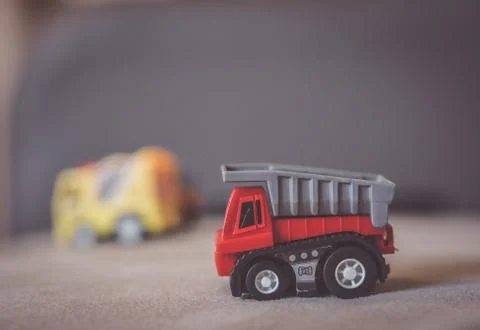 Closeup shot of a plastic red construction truck on a gray surface Stock Photos