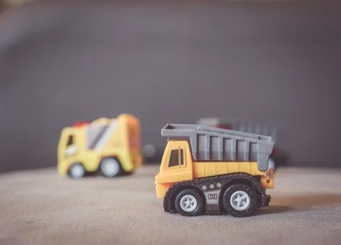 Closeup shot of a plastic yellow construction truck on a gray surface Stock Photos