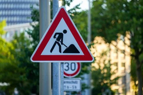 Closeup shot of a red triangular traffic sign of "working on road" with a blur Stock Photos
