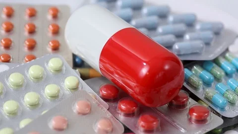 Closeup shot of rotating big pill on pile of medicine blisters Stock Footage 124636337