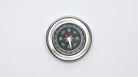 Closeup shot of round magnetic compass on white surface in West Virginia America Stock Footage 310733309