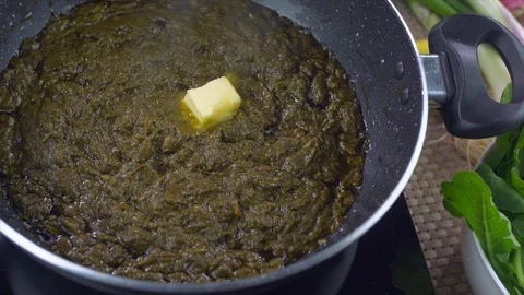 Closeup shot of Sarson ka saag being cooked in a pan - Traditional Punjabi food Video stock 128691299