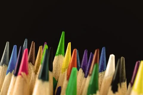 Closeup shot of the sharp tips of colorful school pencils on a black backgrou Stock Photos