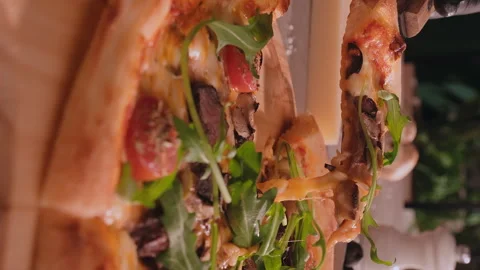 Closeup shot of a slice of cheesy meat pizza with aragula Stock Footage 246497361