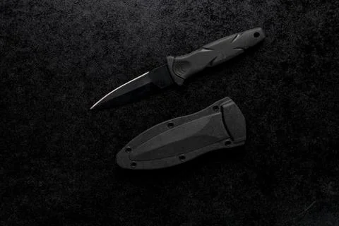 Closeup shot of a small sharp knife with a black handle on a black background Stock Photos