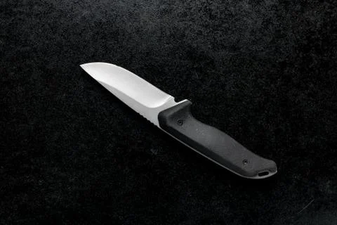 Closeup shot of a small sharp knife with a black handle on a black background Stock Photos