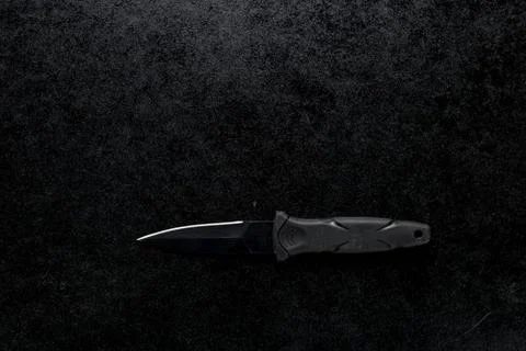 Closeup shot of a small sharp knife with a black handle on a black background Stock Photos