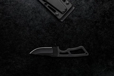 Closeup shot of a small sharp knife with a black handle on a black background Foto stock