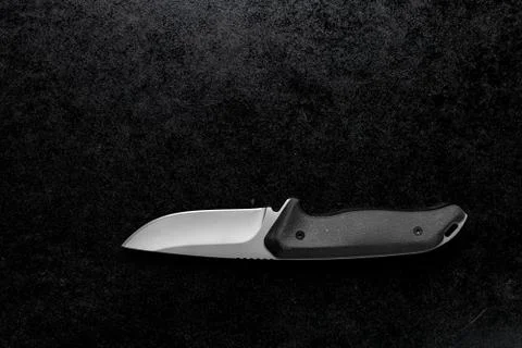 Closeup shot of a small sharp knife with a black handle on a black background Stock Photos