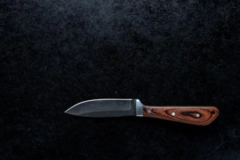 Closeup shot of a small sharp knife with a brown handle  on a black backgroun Photos