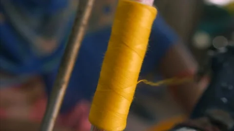 Closeup shot of a spool with thin yellow thread on a professional sewing machine Stock Footage 131311022