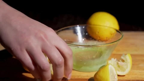 Closeup shot of squeezing yellow ripe lemon with hand, releasing abundant lemon Stock-Footage 336588518