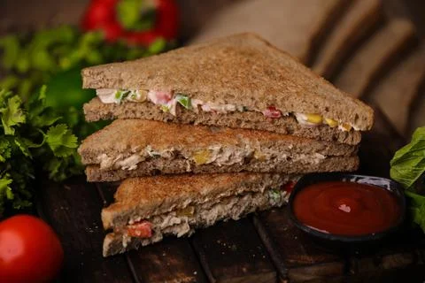 Closeup shot of a stack of cut triangle sandwiches with meat and vegetables near 스톡 사진