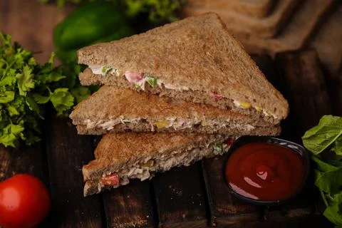 Closeup shot of a stack of cut triangle sandwiches with meat and vegetables near 스톡 사진