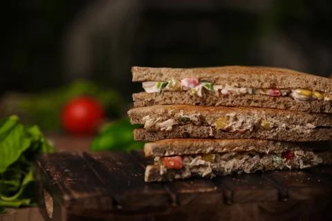 Closeup shot of a stack of cut triangle sandwiches with meat and vegetables 스톡 사진