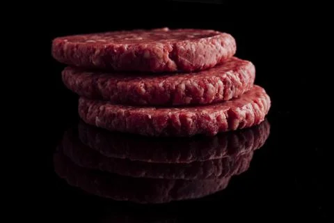 Closeup shot of a stack of raw burger patties on a black surface Foto stock