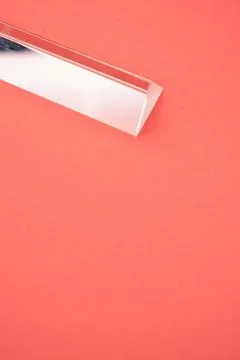Closeup shot of a triangular glass prism isolated on a red background Stock Photos