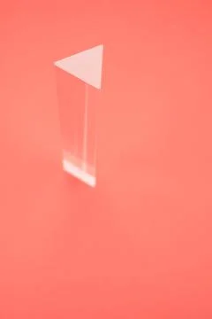 Closeup shot of a triangular glass prism isolated on a red background Stock Photos