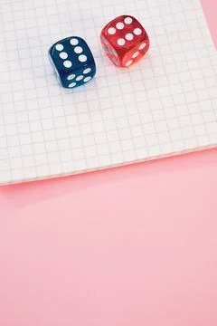 Closeup shot of two rolling dices on a notebook isolated on a pink background Stock Photos