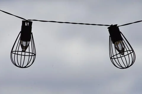 Closeup shot of two string lights with gray sly in the background Stock Photos