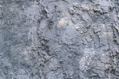 Closeup shot of an uneven and bumpy gray wall of a cliff Stock Photos