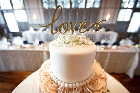 Closeup shot of a wedding cake with a love sign on a blurred background Stock Photos