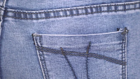 Closeup shot of woman's hand put a mobile phone into her jeans pocket. Rear view Stock Footage 125480224