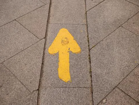 Closeup shot of a yellow pointer sign on the ground Stock Photos