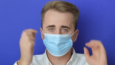 Closeup shot of a young man using a medical mask during the Covid-19 pandemic Stock Footage 218985826