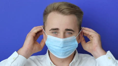 Closeup shot of a young man using a medical mask during the Covid-19 pandemic Stock Footage 221540134