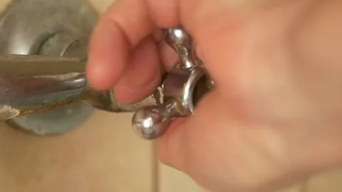 A closeup shows a hand skillfully adjusting a faucet to control the water flow Stock Footage 288993070