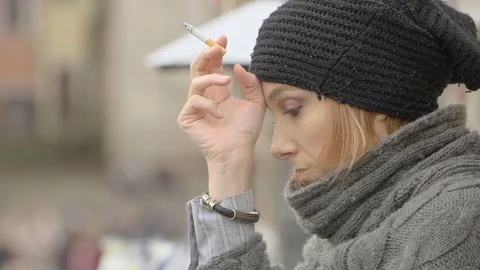 Closeup side portrait of a sad young woman smoking in the street: loneliness  Stock Footage 82940147