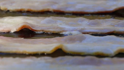 Closeup side view of bacon strips sizzling on hot griddle outside Stock Footage 302188822