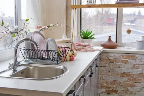 Closeup Side view of Kitchen sink , flowers and plates near the window Stock Photos