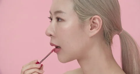 Closeup side view portrait of Asian woman applying lipstick or gloss on lips. Stock Footage 206105036