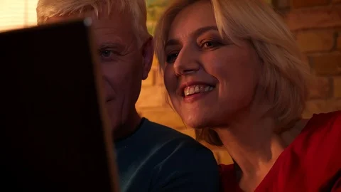 Closeup side view shoot of aged happy couple watching a movie on the laptop Video stock 107014173