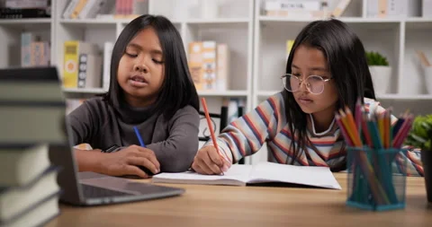 Closeup side view of Two Asian student girls sitting at desk at home.  Stock Footage 202246402
