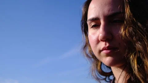 Closeup side view of young pretty caucasian girl looking at camera with sky b Stock Footage 131050802