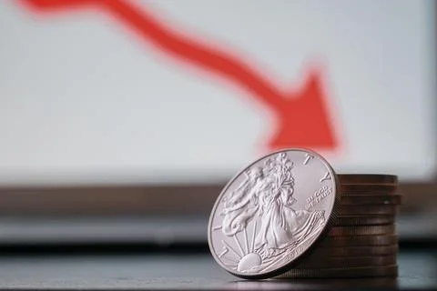 Closeup of silver coins with a drop in value on the computer with red arrow Stock Photos