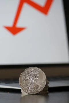 Closeup of silver coins with a drop in value on the computer with red arrow Stock Photos