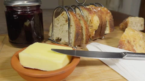 Closeup of a simple breakfast – a jar of jam jelly, bread slices and butter. Vídeos de archivo 295774921