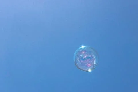 Closeup of single bubble floating in background of blue sky Stock Photos