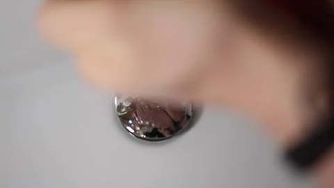Closeup sink drain as clear water rushes down reflecting a blurry face intense a Video stock 309334533
