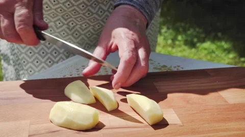 Closeup Of Skilled Hands Slicing Peeled Potatoes On Wooden Surface In Sunlight Stock Footage 326022848