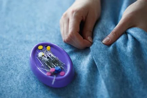 Closeup of skilled tailor hands marking and measuring fabric while making Stock Photos