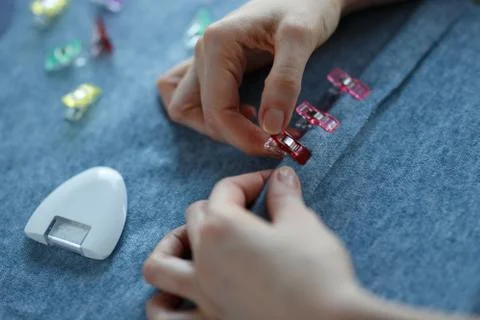 Closeup of skilled tailor hands marking and measuring fabric while making Stock Photos