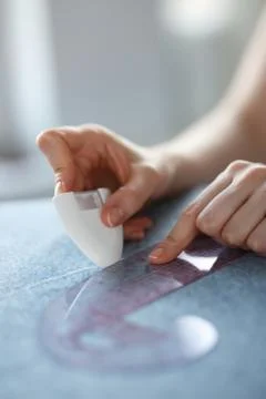 Closeup of skilled tailor hands marking and measuring fabric while making Stock Photos