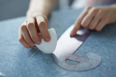 Closeup of skilled tailor hands marking and measuring fabric while making Stock Photos