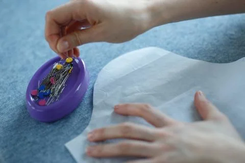 Closeup of skilled tailor hands marking and measuring fabric while making Stock Photos